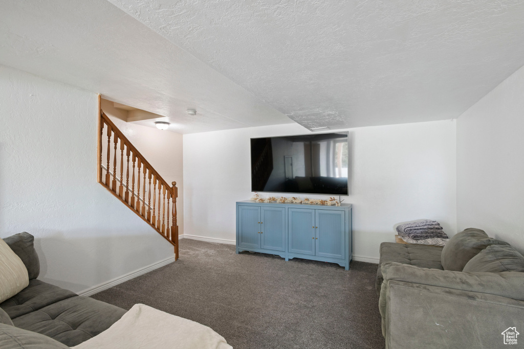 Carpeted living area featuring baseboards, stairway, and a textured ceiling
