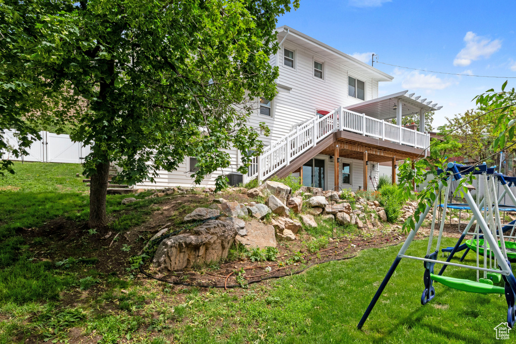 Rear view of property with a wooden deck, stairway, and a playground