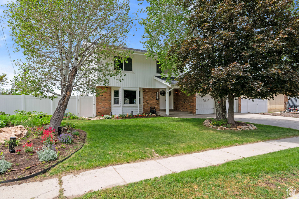 View of front of house with brick siding, driveway, and a garage