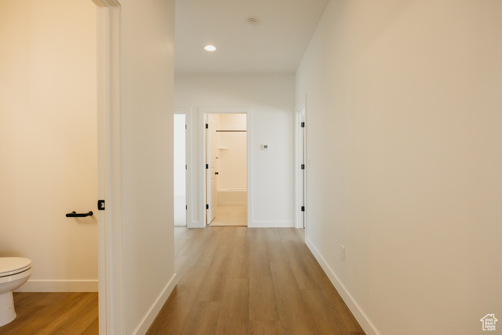 Hallway featuring light wood-type flooring, recessed lighting, and baseboards