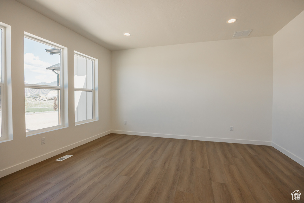 Unfurnished room with wood finished floors, baseboards, and recessed lighting