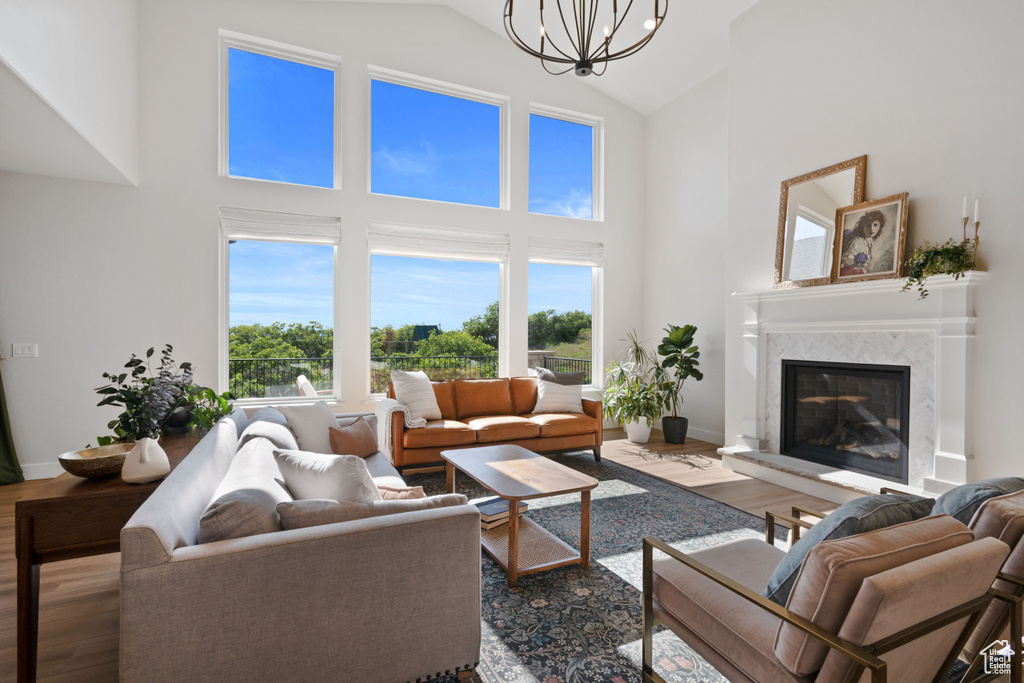 Living area featuring high vaulted ceiling, wood finished floors, a chandelier, a fireplace, and baseboards