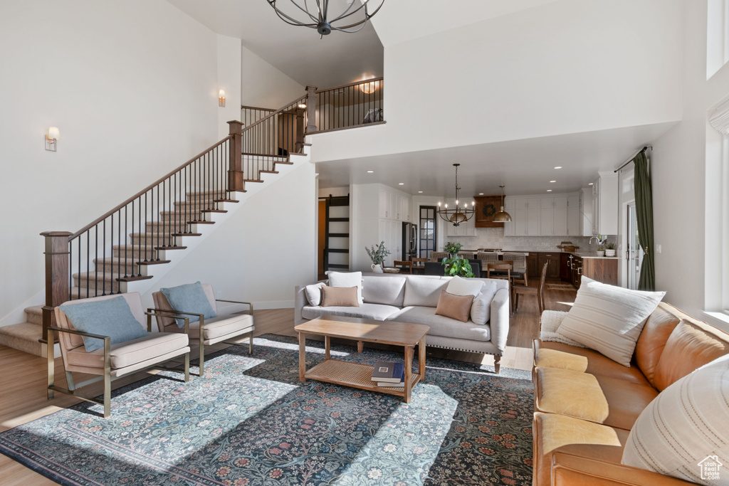 Living room featuring a chandelier, stairs, wood finished floors, and a high ceiling