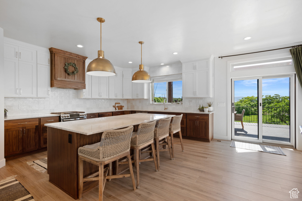 Kitchen featuring stainless steel gas stove, a breakfast bar, backsplash, a sink, and a kitchen island