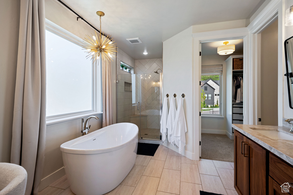 Full bathroom featuring a shower stall, vanity, a freestanding bath, a chandelier, and baseboards