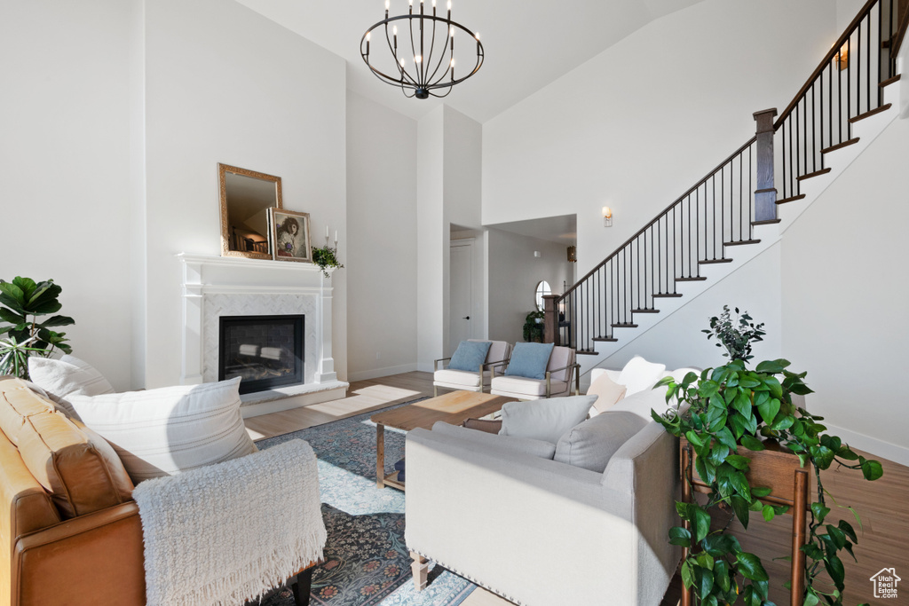 Living room with stairs, high vaulted ceiling, baseboards, wood finished floors, and a high end fireplace