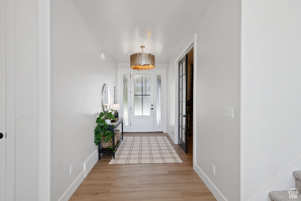 Entrance foyer with baseboards, light wood finished floors, and a chandelier