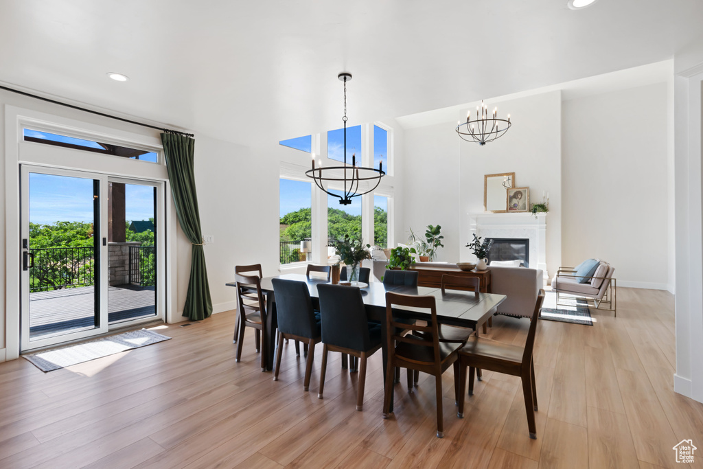 Dining area featuring a chandelier, light wood-type flooring, baseboards, recessed lighting, and a glass covered fireplace