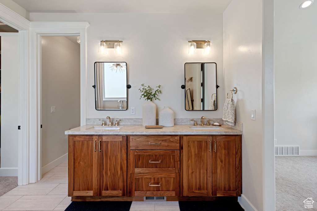 Bathroom featuring double vanity, baseboards, and tile patterned floors