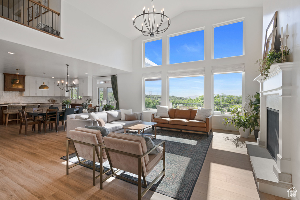 Living area with a chandelier, light wood-style floors, a fireplace, and high vaulted ceiling