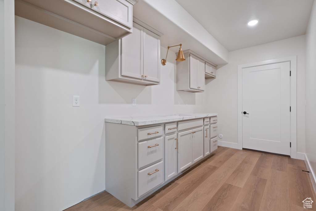 Kitchen with light wood-type flooring, baseboards, white cabinets, and recessed lighting
