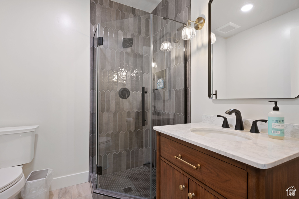 Bathroom with vanity, toilet, a shower stall, and baseboards
