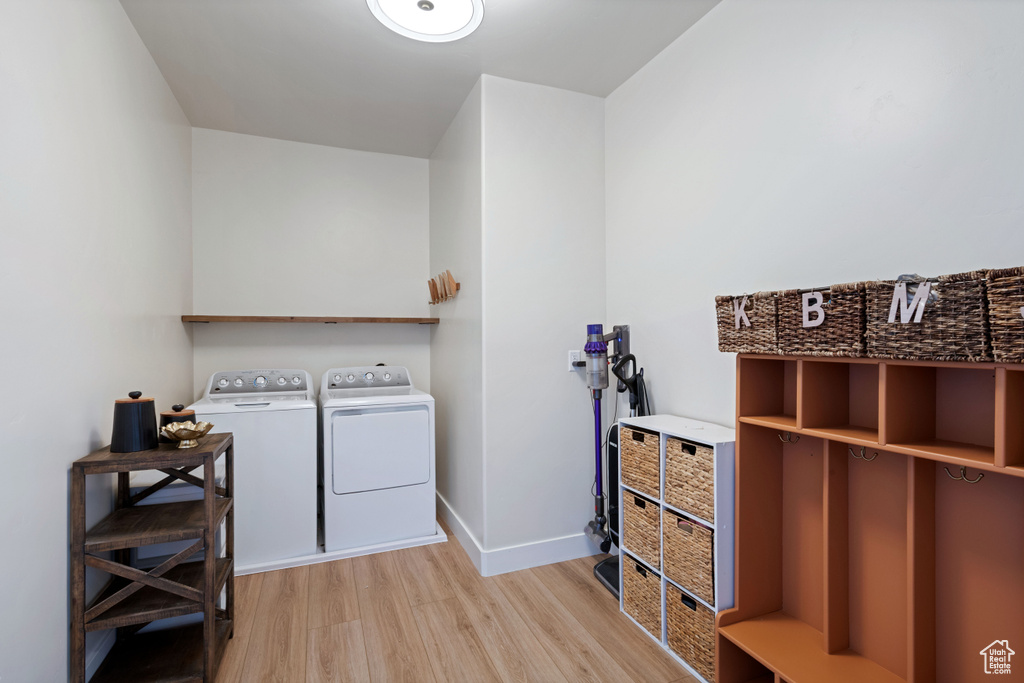 Laundry room featuring light wood-style flooring, baseboards, and separate washer and dryer