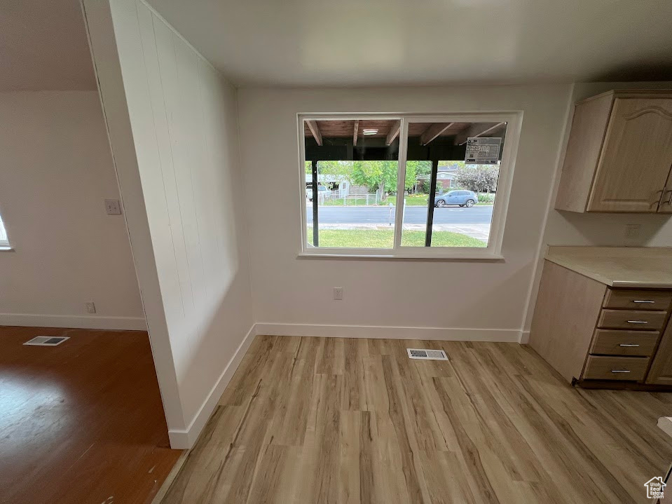 Unfurnished dining area with light wood-style flooring and baseboards