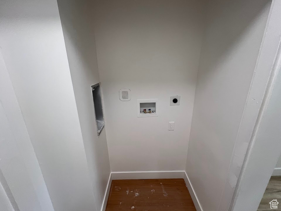 Washroom with hookup for an electric dryer, washer hookup, wood finished floors, and baseboards