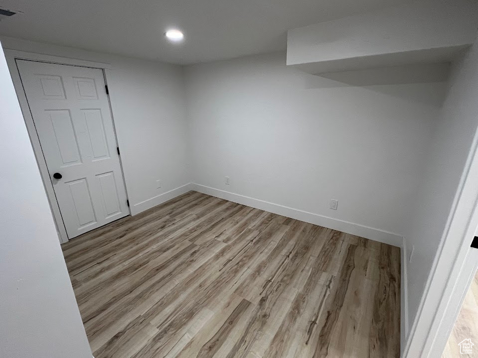 Empty room featuring wood finished floors, baseboards, and recessed lighting