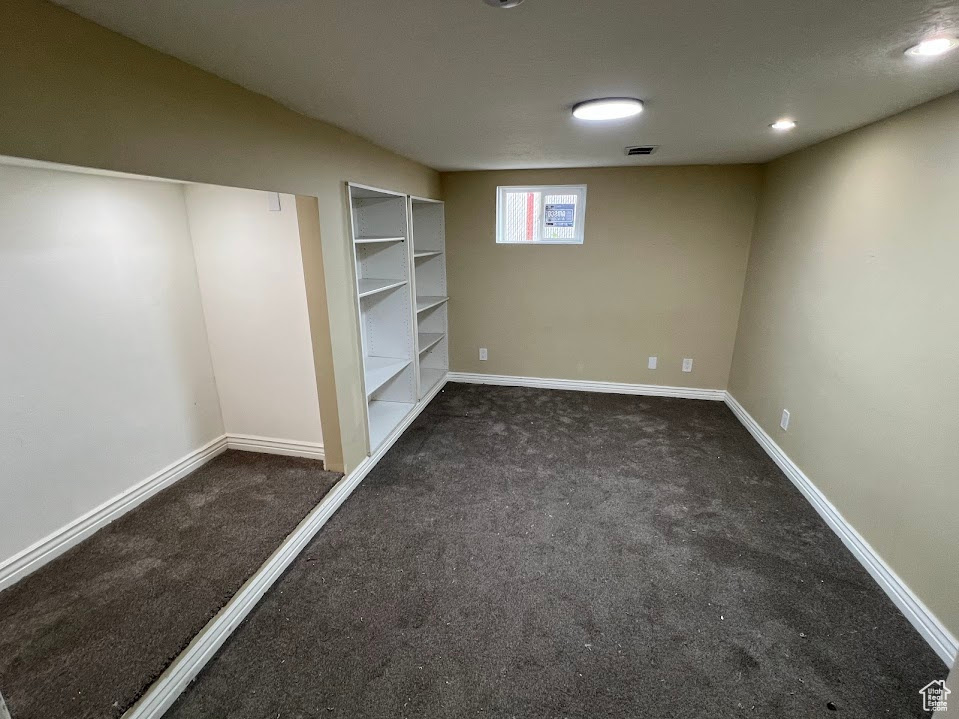 Below grade area with carpet floors, baseboards, and built in shelves