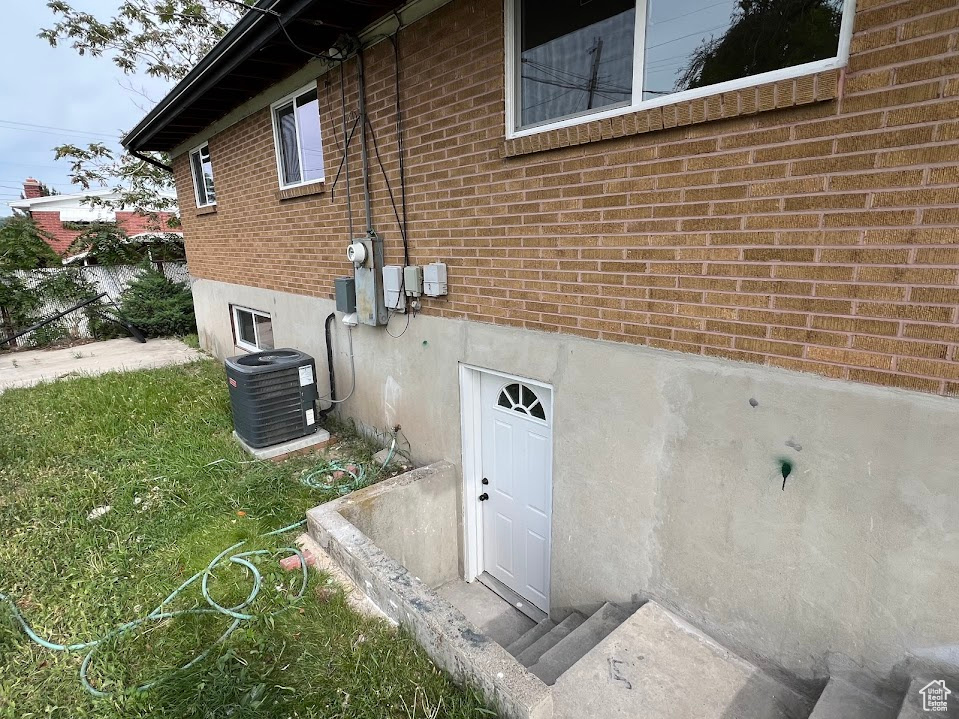 View of side of property featuring central air condition unit and brick siding