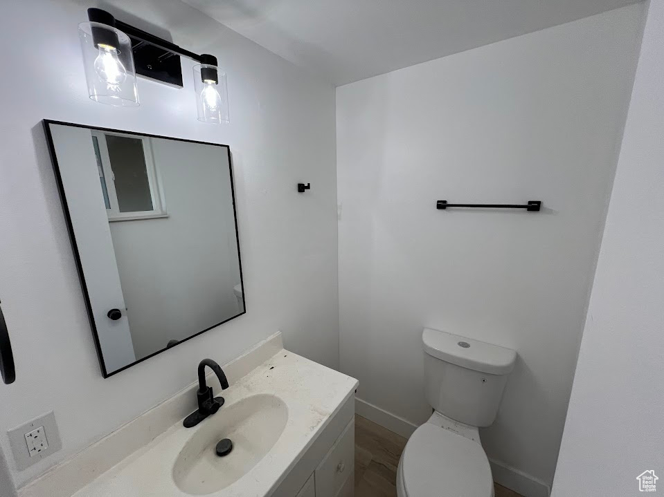 Bathroom with toilet, vanity, and baseboards