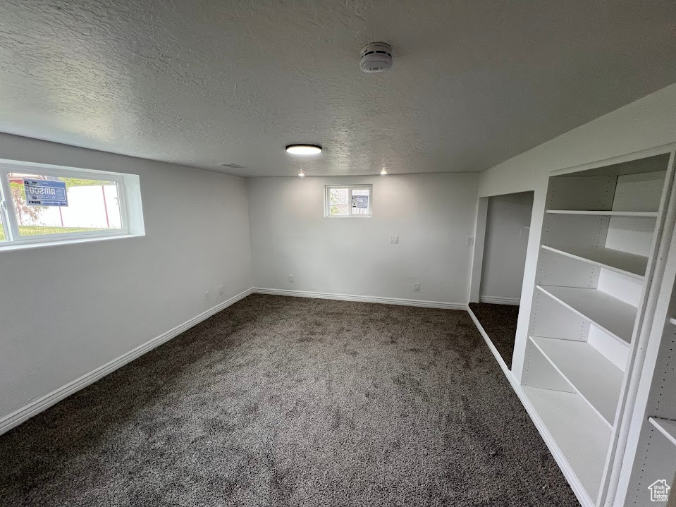 Unfurnished bedroom with carpet floors, a textured ceiling, and baseboards