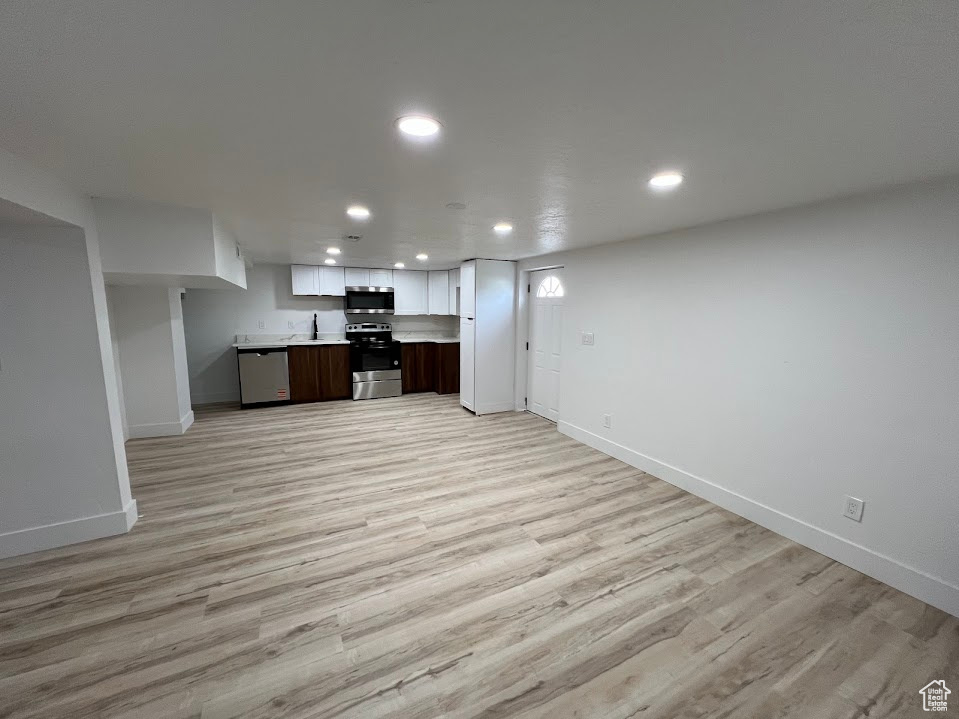 Kitchen with stainless steel appliances, light countertops, baseboards, recessed lighting, and light wood-type flooring