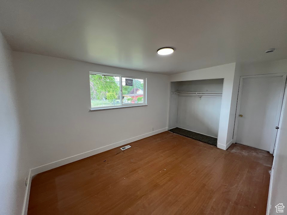 Unfurnished bedroom with wood finished floors, a closet, and baseboards