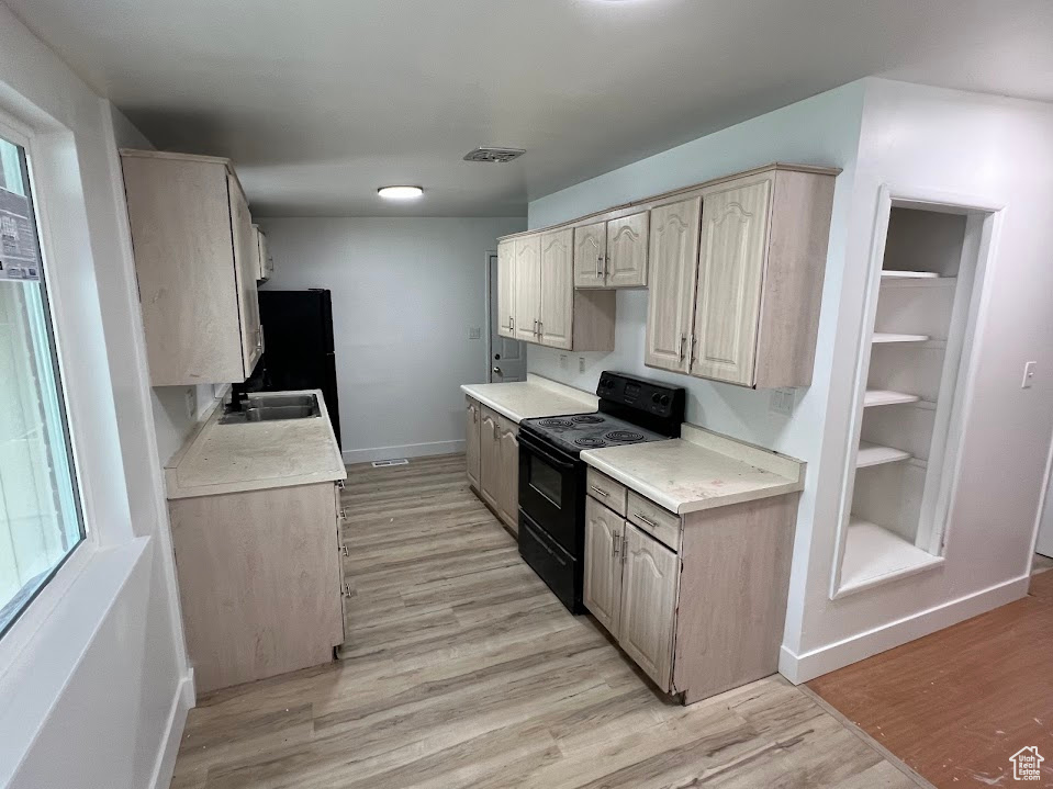 Kitchen featuring black appliances, baseboards, light countertops, and light wood finished floors