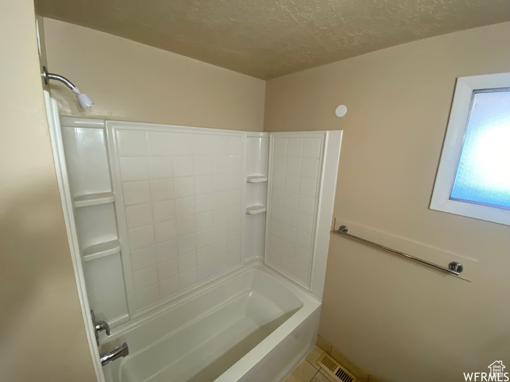 Bathroom with shower / tub combination and a textured ceiling