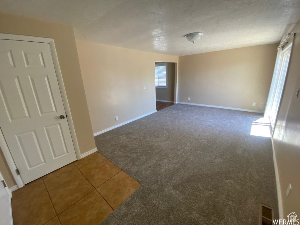 Carpeted empty room featuring baseboards and tile patterned floors