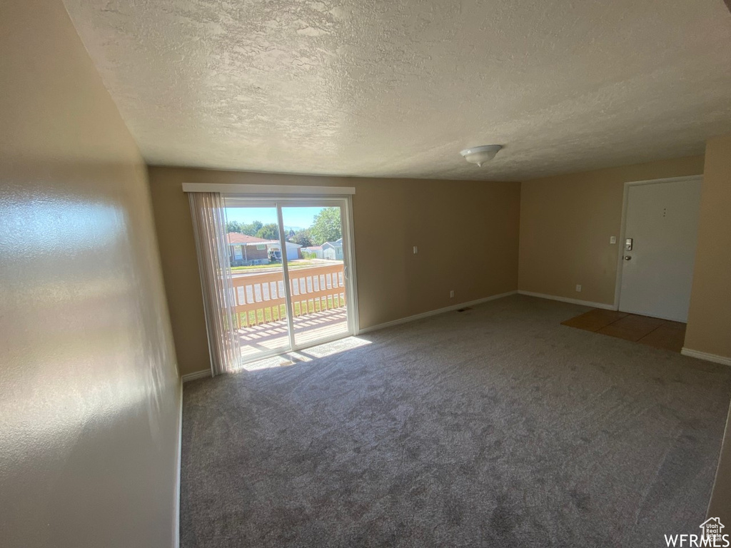 Carpeted empty room featuring a textured ceiling and baseboards