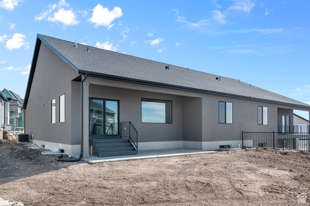 Back of house featuring cooling unit, stucco siding, and a shingled roof