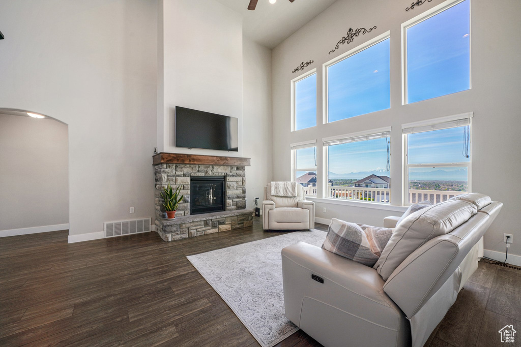 Living area featuring a high ceiling, baseboards, wood finished floors, arched walkways, and a fireplace