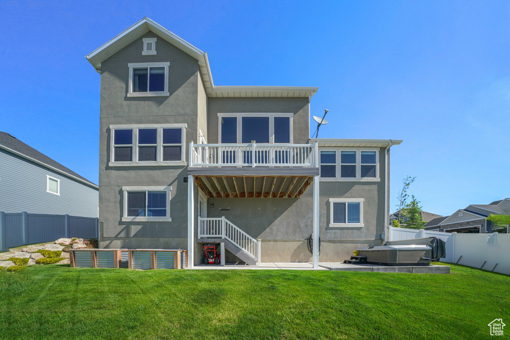 Rear view of property with stucco siding and a hot tub