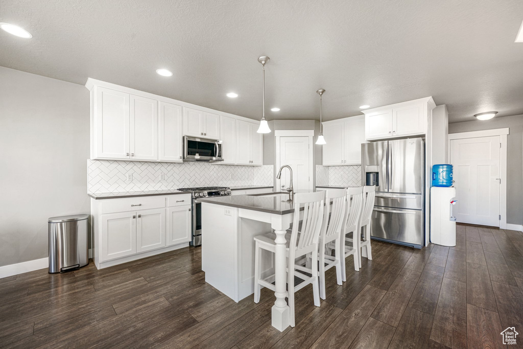 Kitchen with stainless steel appliances, dark wood finished floors, white cabinetry, and recessed lighting