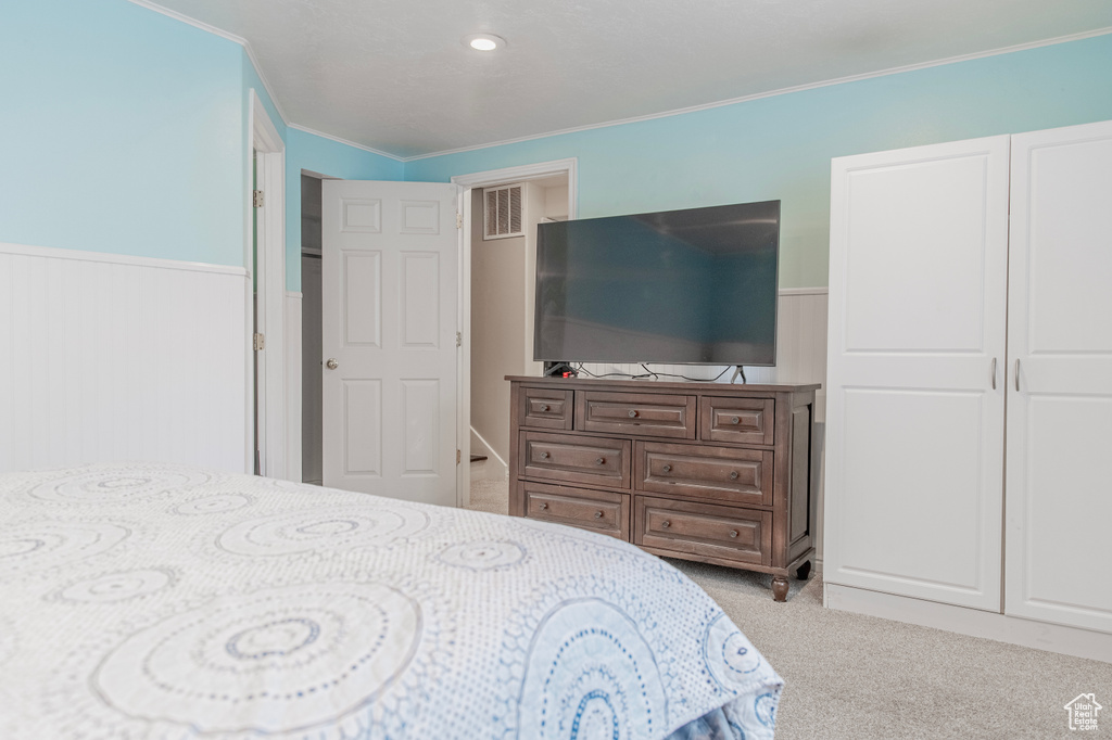 Carpeted bedroom with ornamental molding and a wainscoted wall