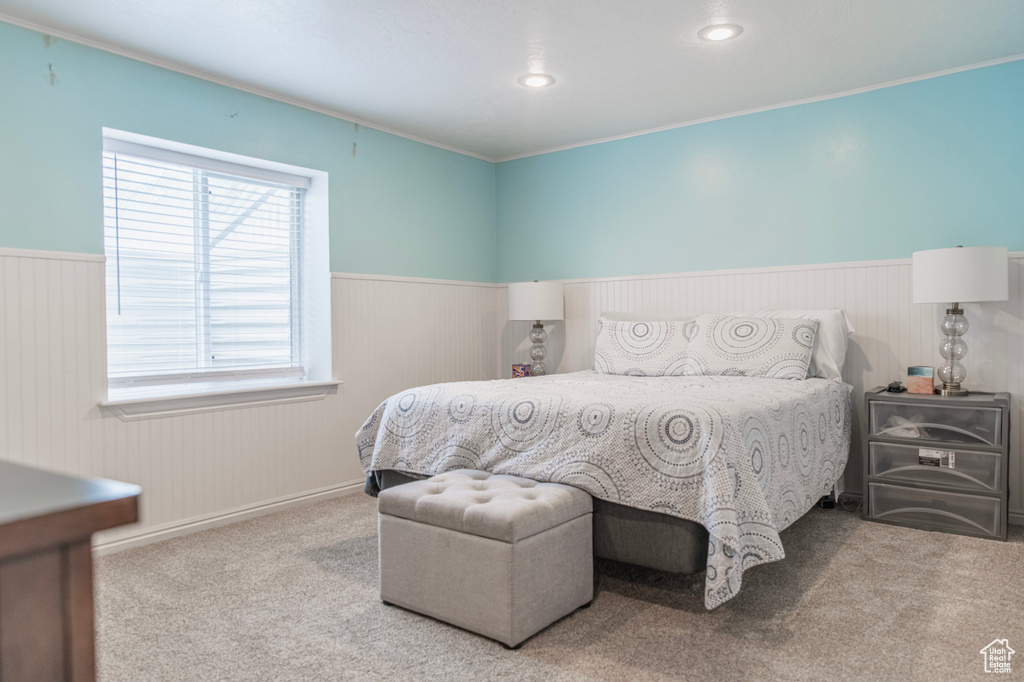 Carpeted bedroom featuring a wainscoted wall, recessed lighting, and ornamental molding