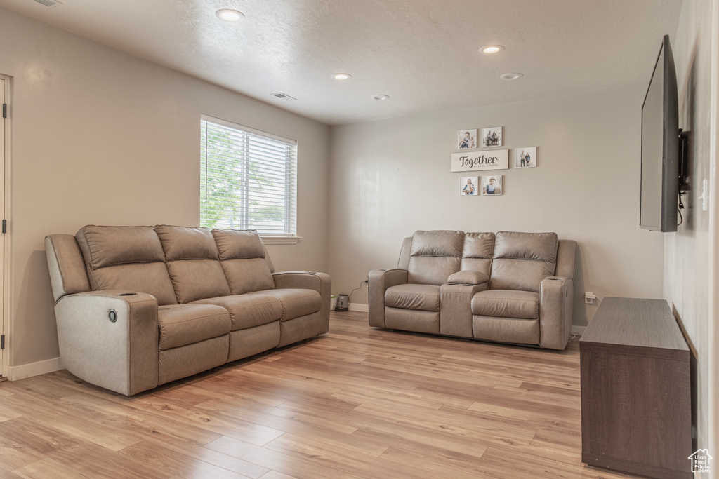 Living area with light wood-type flooring, baseboards, and recessed lighting