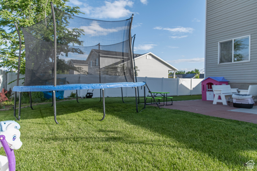 View of yard featuring a trampoline and a patio
