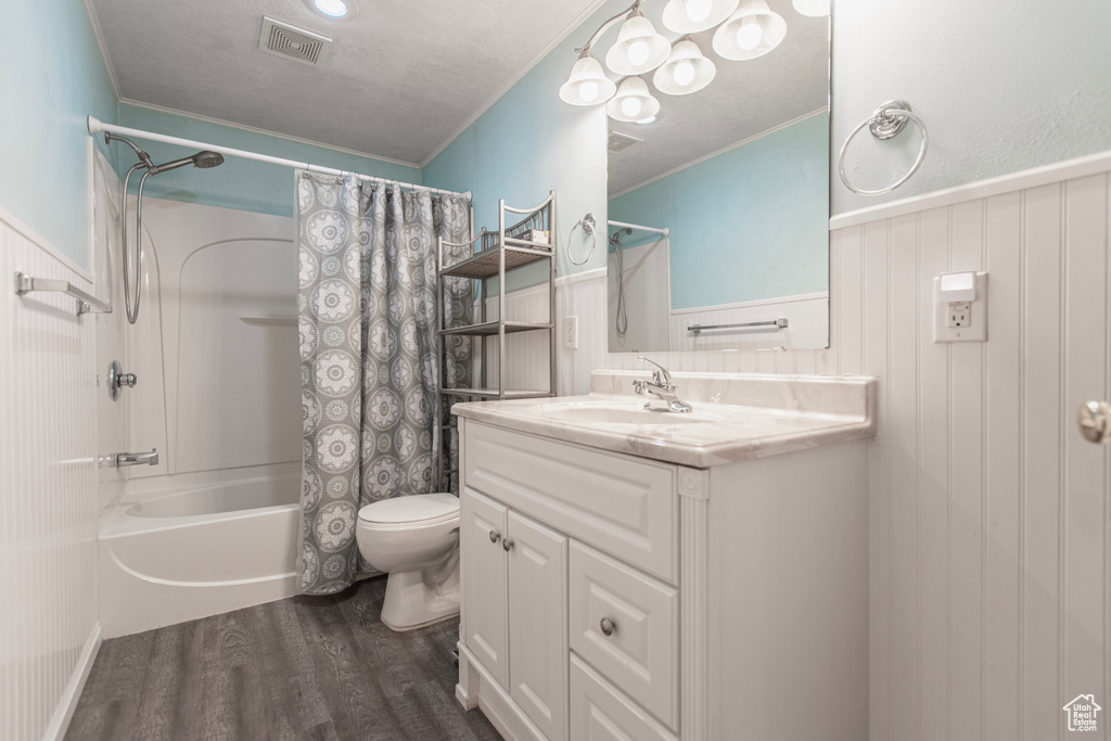 Bathroom with wood finished floors, vanity, toilet, ornamental molding, and shower / tub combo with curtain