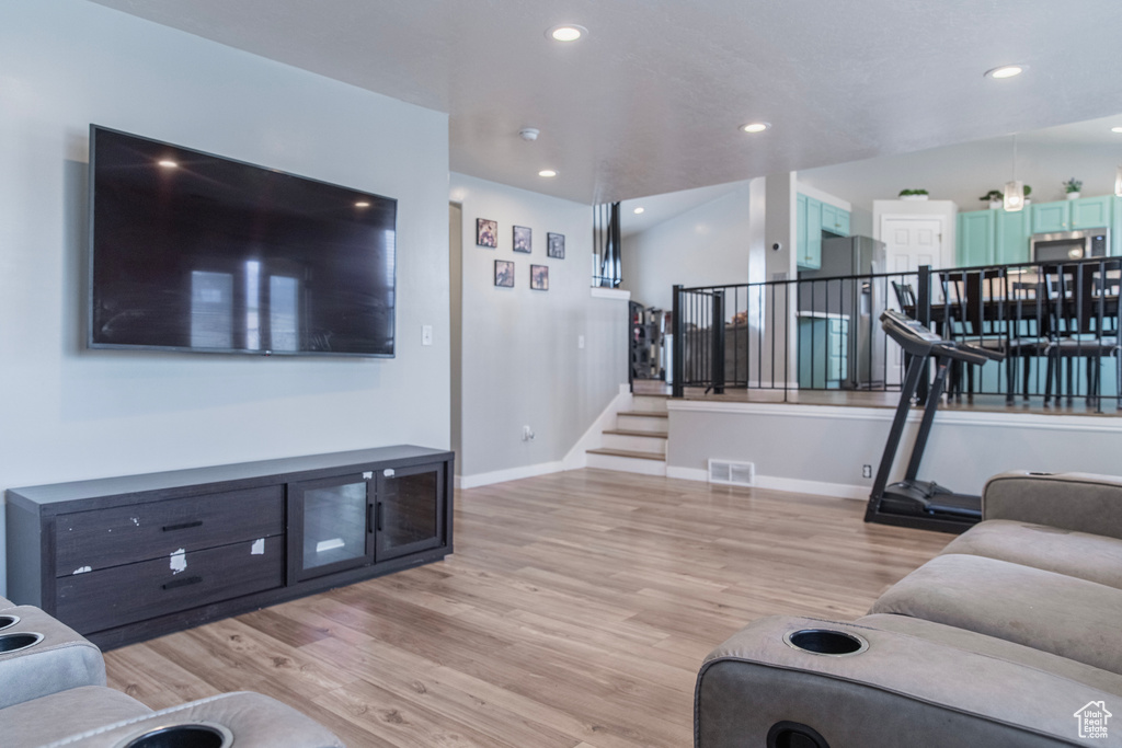 Living area with light wood finished floors, stairway, baseboards, and recessed lighting