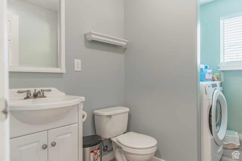 Half bath featuring washer / clothes dryer, toilet, and vanity