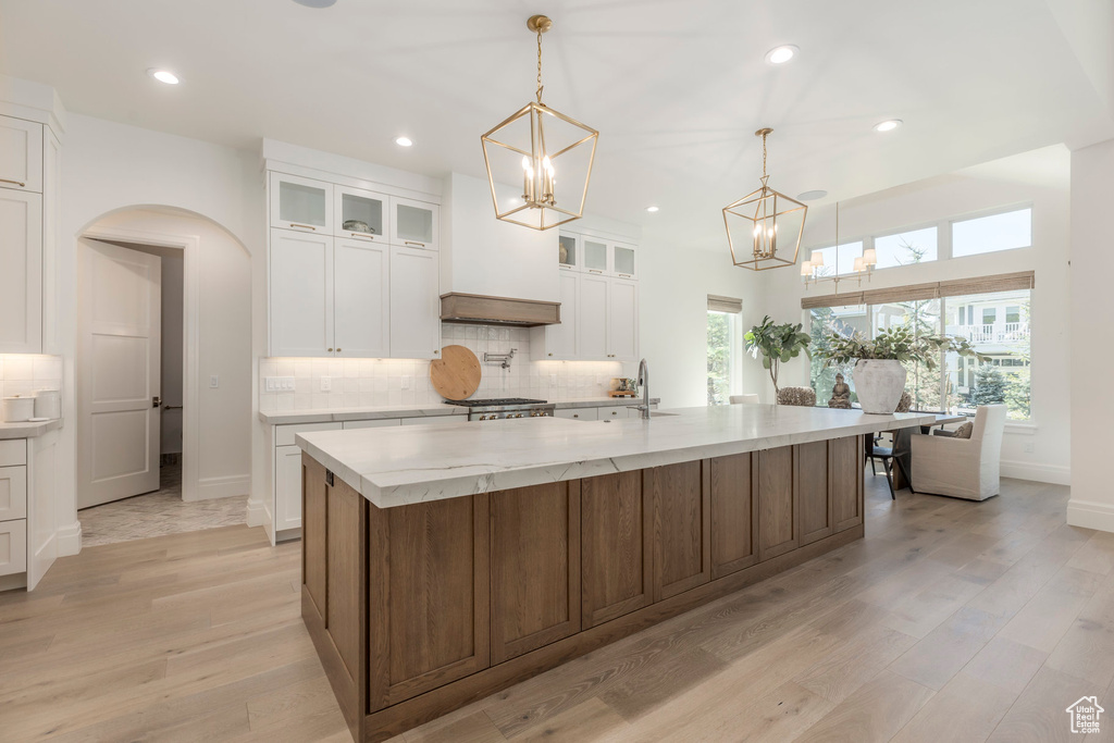 Kitchen featuring a chandelier, white cabinetry, tasteful backsplash, light wood-type flooring, and recessed lighting
