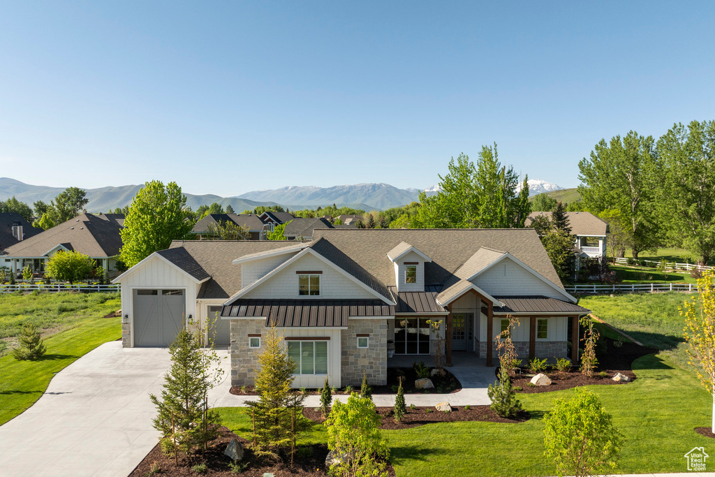 View of front of home featuring concrete driveway, a standing seam roof, roof with shingles, a mountain view, and stone siding