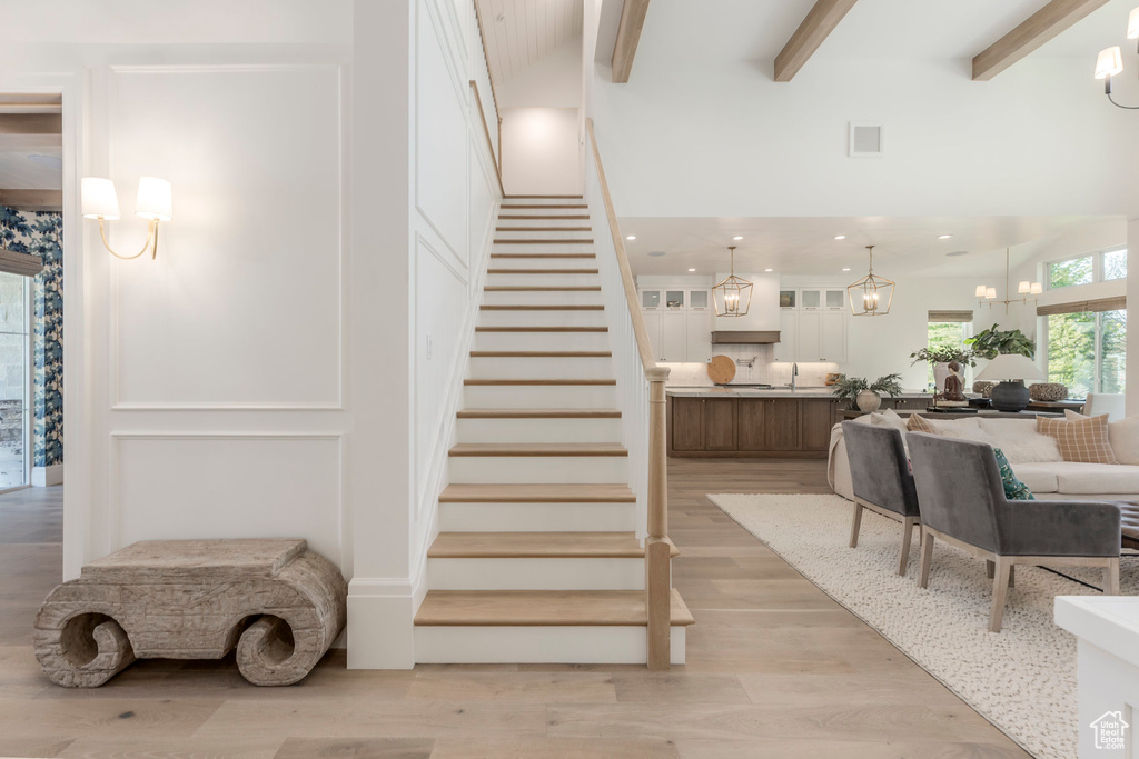 Stairs featuring wood finished floors, beamed ceiling, and recessed lighting