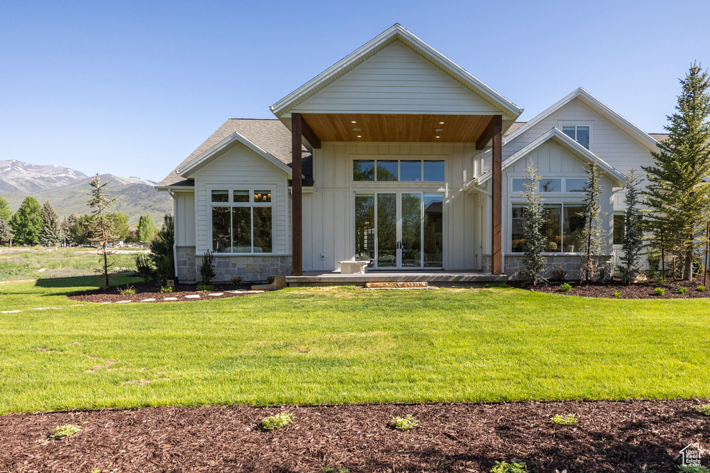Rear view of house with board and batten siding, a lawn, and a mountain view