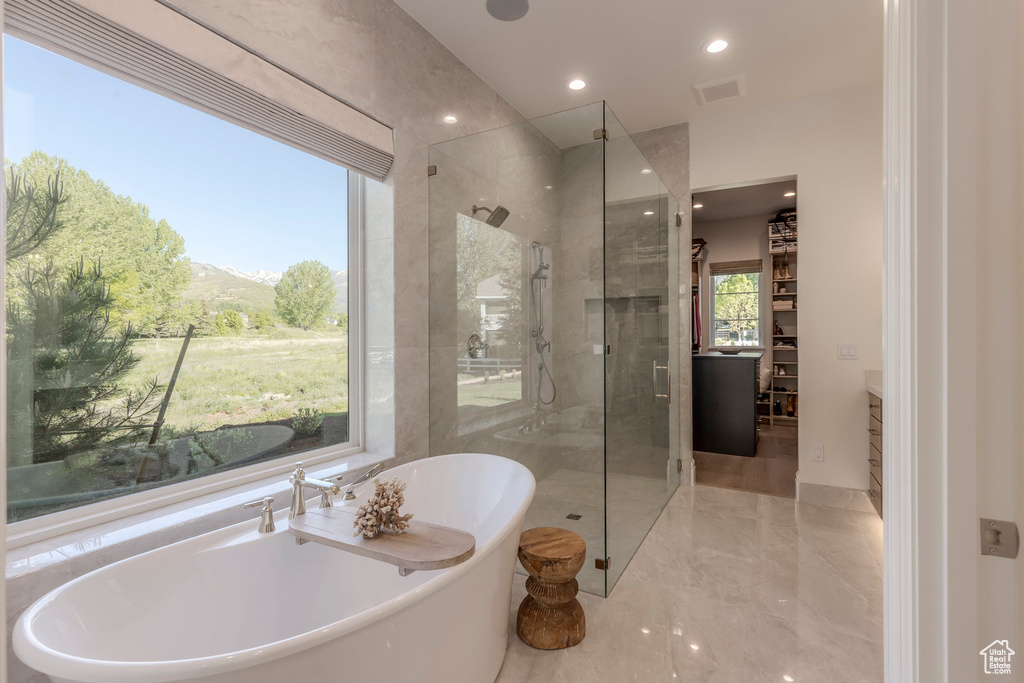Bathroom featuring a stall shower, a freestanding tub, marble tiled flooring, and recessed lighting