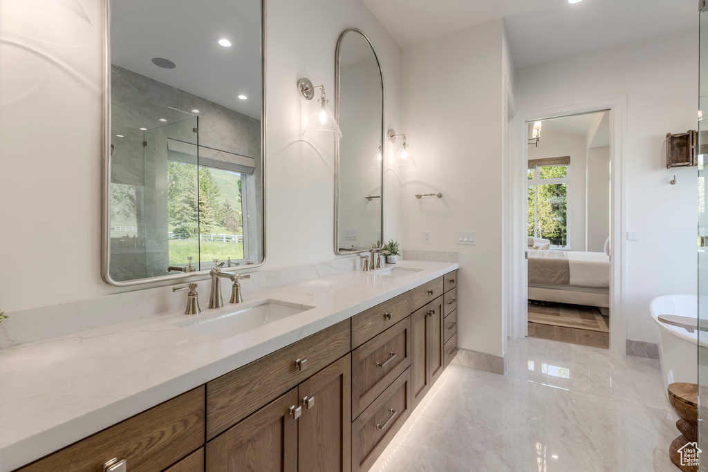 Bathroom with ensuite bathroom, double vanity, marble tiled flooring, recessed lighting, and a freestanding bath