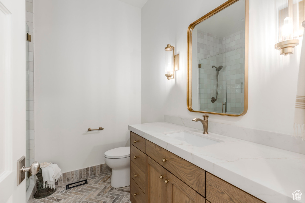 Bathroom with toilet, vanity, and a tile shower