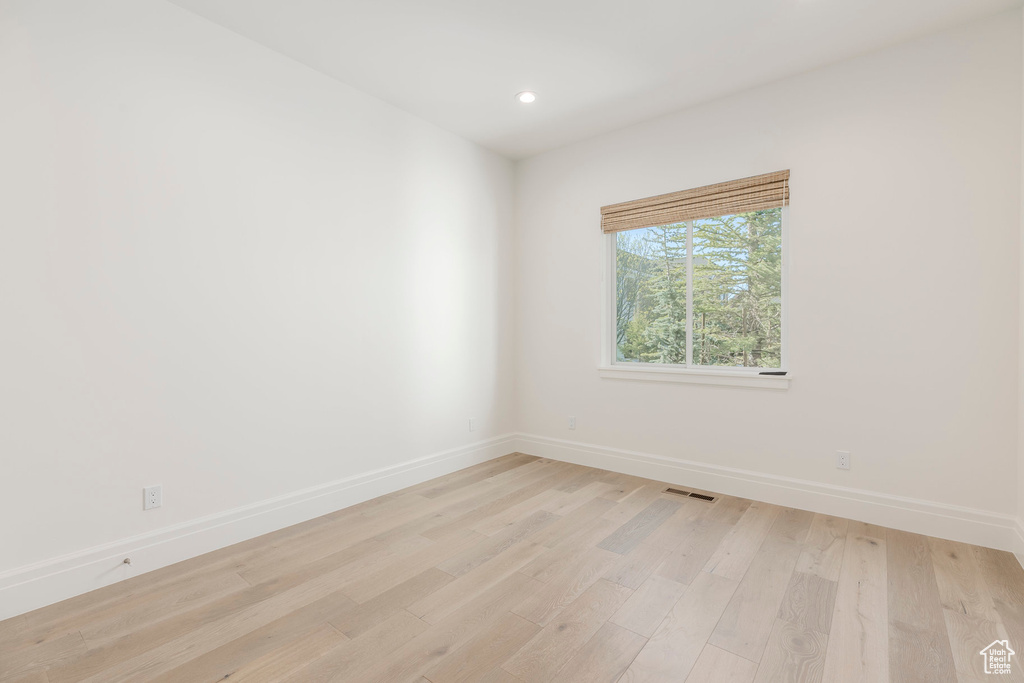 Empty room featuring baseboards, light wood-style floors, and recessed lighting