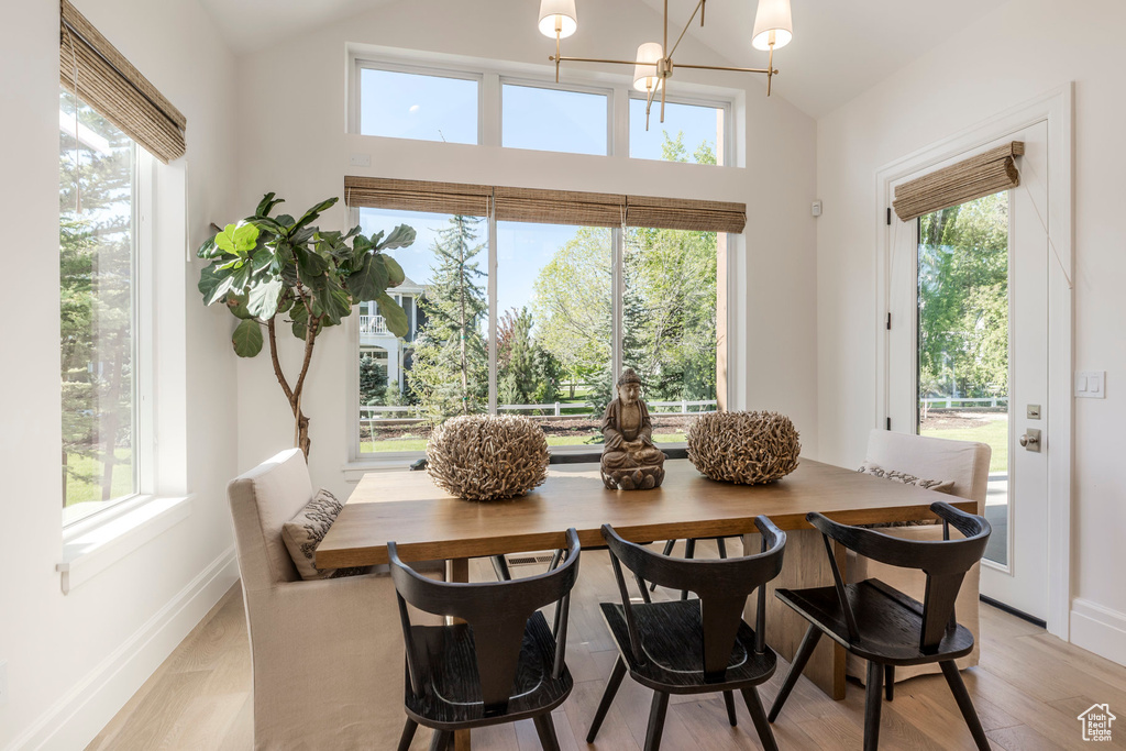 Dining space with a chandelier, plenty of natural light, baseboards, and lofted ceiling